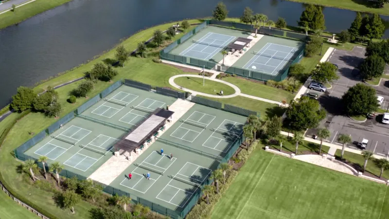 Sport courts surrounded by well manicured lawns and lakes.