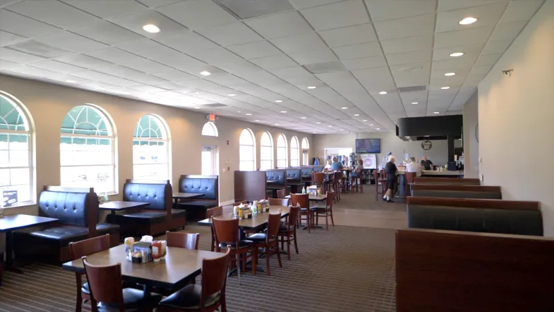 Modern dining area at Spruce Creek South with booths and tables and a bar counter in the background.