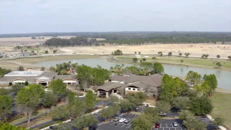Overview of the Stone Creek clubhouse, parking area and lake.