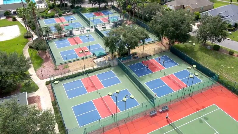 Spruce Creek Country Club pickleball courts nestled among lush trees, with inviting homes in the background.