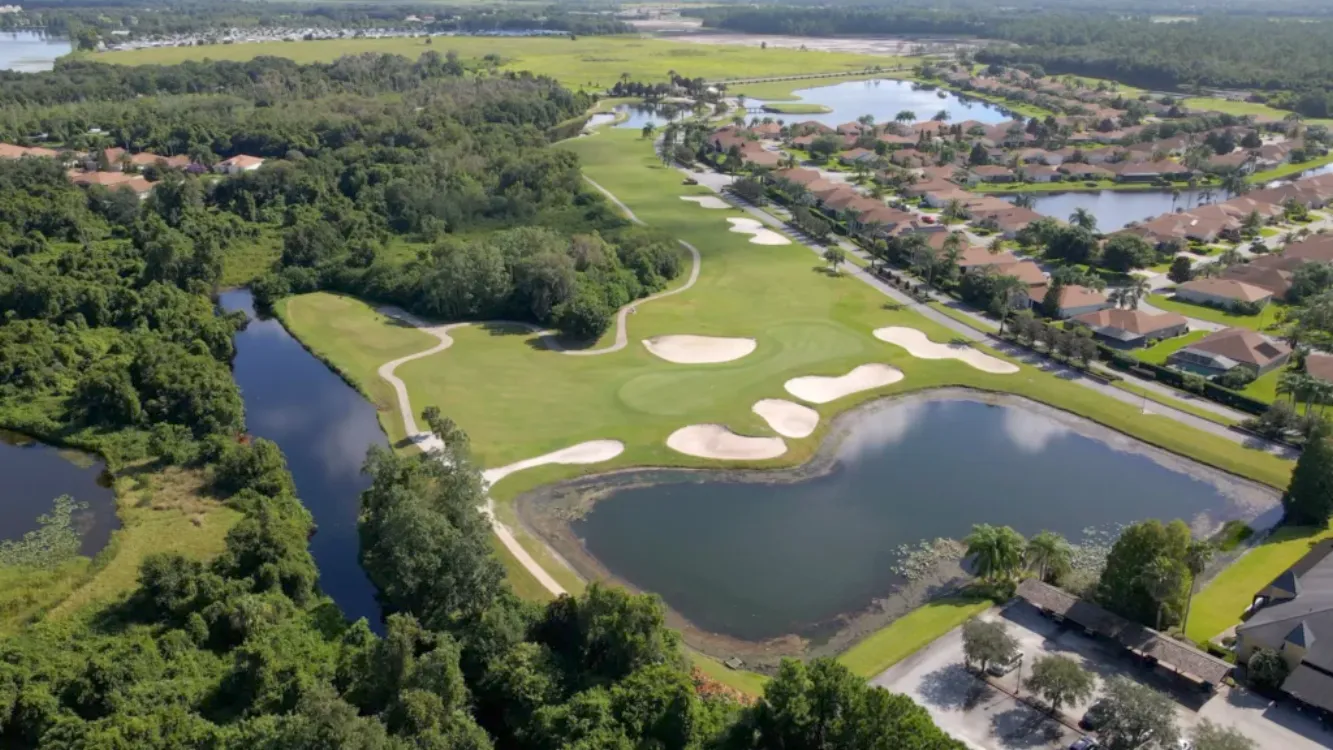 Golf course surrounded by lush greenery, water features and homes.