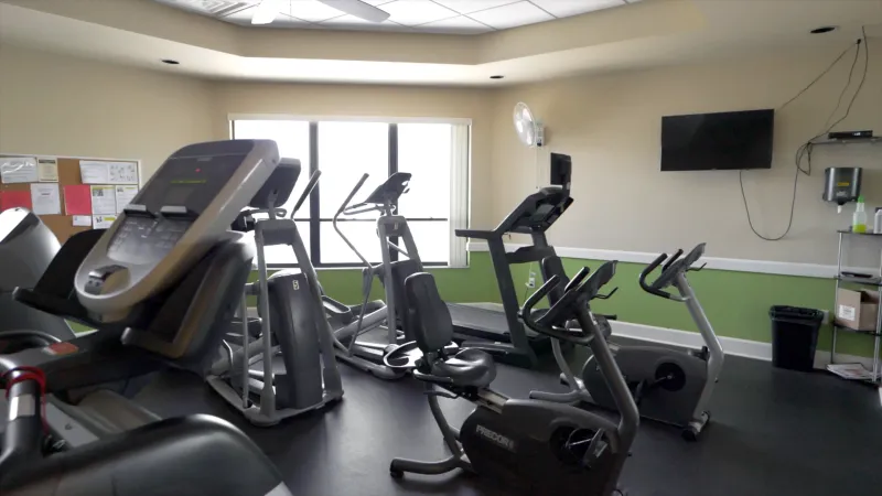 Exercise equipment in the Sandpiper Golf & Country Club gym with TV for resident use.