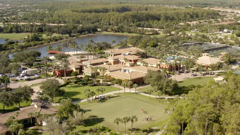 Aerial view of Pelican Preserve's  bridge over a lake, adjacent to a golf course and villas.