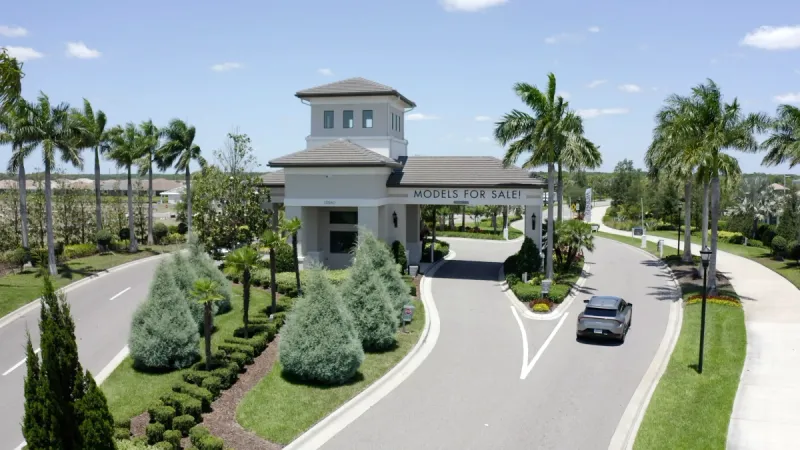 Lush and meticulously crafted landscaping surrounds the guard entrance of a gated community.