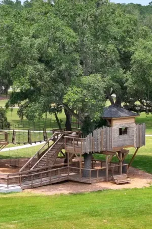 A wooden playground at Summer Bay at Grand Oaks with various play structures and equipment.