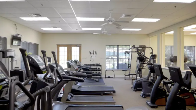 A gym with a variety of exercise equipment including cardio machines and weights.