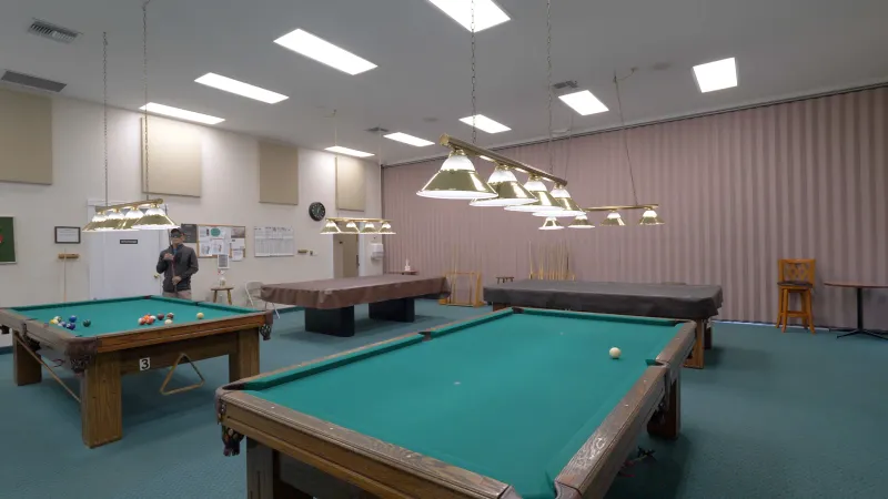 Well lit billiard room with pool tables and overhead lighting creating a fun and inviting space for socializing.