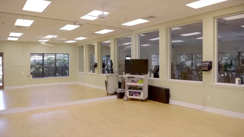 An aerobics and yoga studio with wood floors and a wall-length mirror.