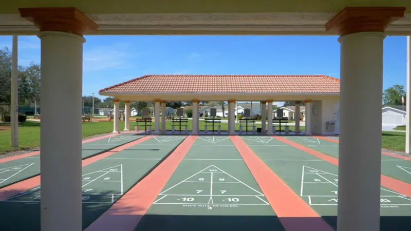 View from a shaded pavilion of a shuffleboard court with multiple lanes within Spruce Creek South.