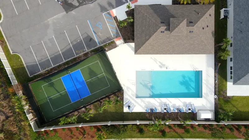 Matanzas Lakes community pool surrounded by lounge chairs and umbrellas with a sport court next to it.