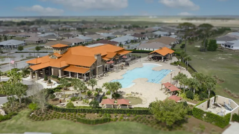 Aerial view of the On Top of the World clubhouse with a large sparkling blue pool.