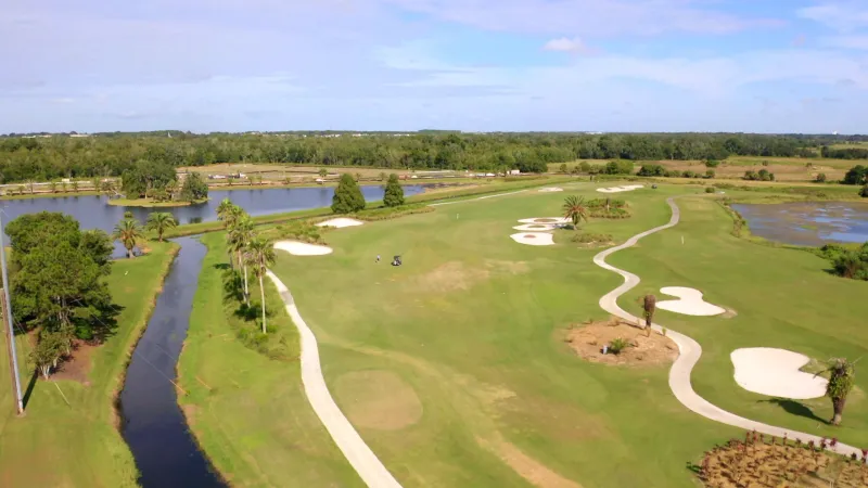 Panoramic view of a golf course surrounded by tranquil lakes, adding to the scenic beauty of the greens.