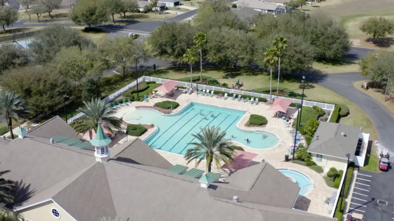 A large pool with lap lanes situated behind a community clubhouse.