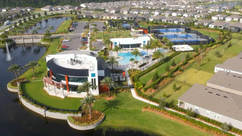 Aerial view of Del Webb eTown's modern community clubhouse surrounded by a landscaped pool and tennis courts.