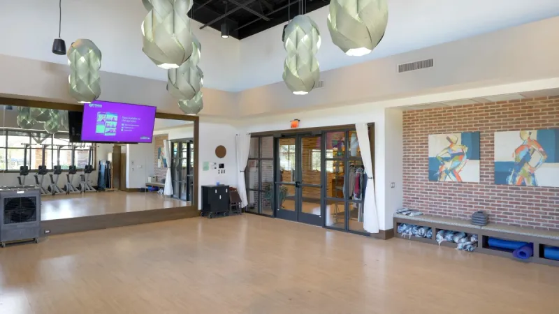 A well-lit aerobics studio with a large mirror and television for classes.