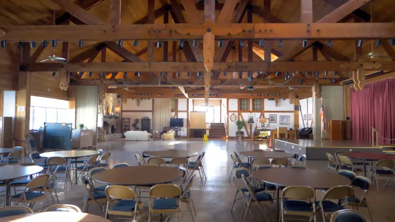 Ballroom at Highland Fairways with wood beam ceiling and tables and chairs.