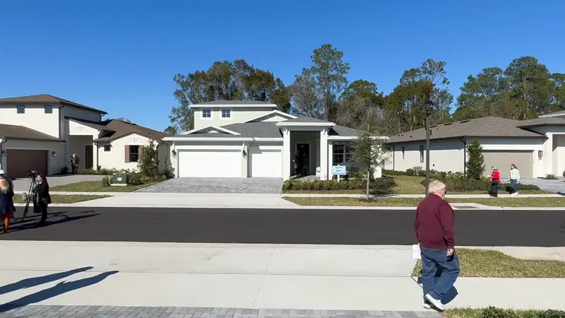 Street-level view of a new home with a white exterior and a three-car garage in the Cresswind DeLand 55+ community.