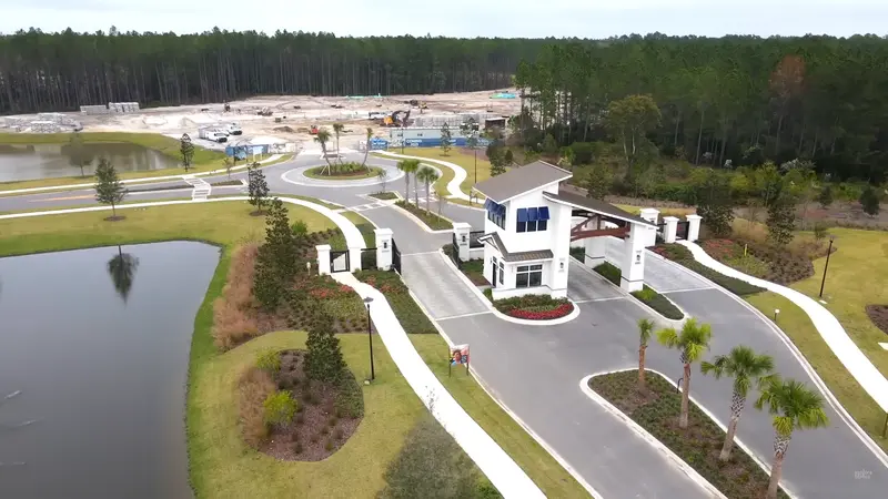 The main entrance of the Del Webb Wildlight community, with a white modern guardhouse and palm-lined street.