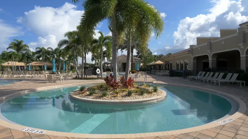 Resort-style pool area at Valencia Cove with palm trees and lounge chairs.