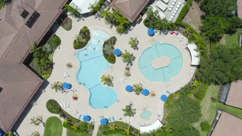 Two distinct Del Webb Southshore Falls pools and a hot tub are enveloped by lush landscaping.