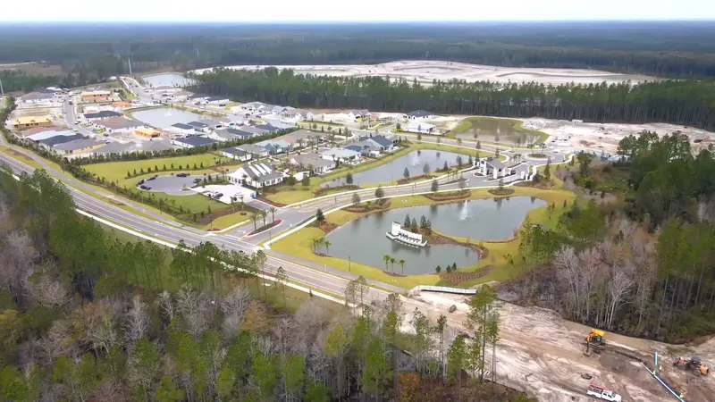 An aerial view of Del Webb Wildlight community, showing homes, roads, and ponds amidst a forested landscape.