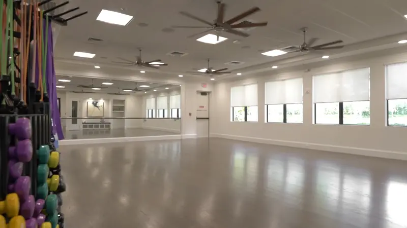 A spacious aerobics room with mirrored walls and exercise equipment.