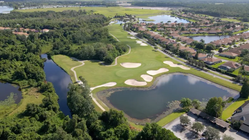 Lake Ashton golf course surrounded by lush greenery, water features and homes.