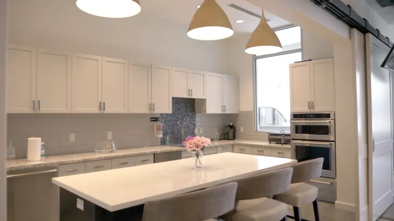 A community kitchen shines with modern appliances, ample counter space and a welcoming bar area to sit at.