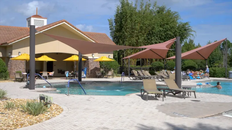 At the community pool, you'll find sunshades, comfortable lounge chairs, and seating areas adorned with bright yellow umbrellas.
