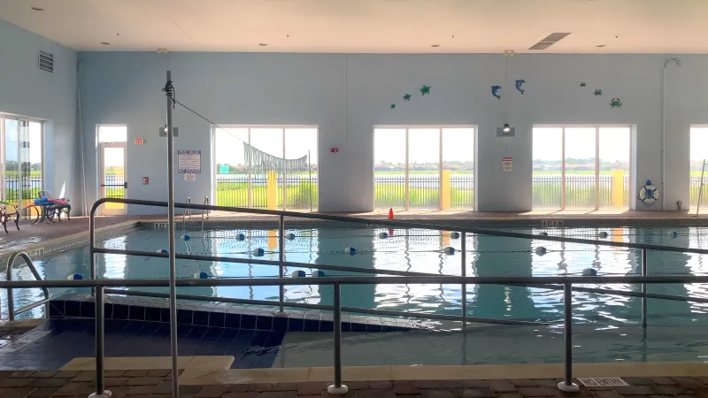 Indoor pool with lap lanes and a beautiful view of the lake outside.