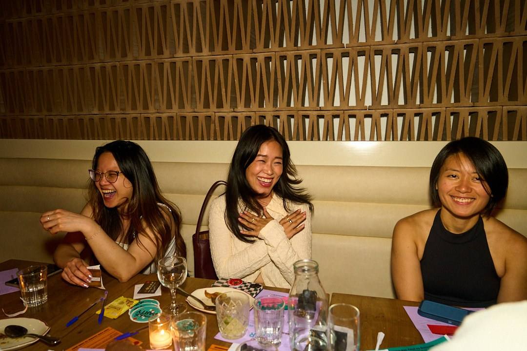 Three women laughing on a banquette at a women-only Timeleft dinner