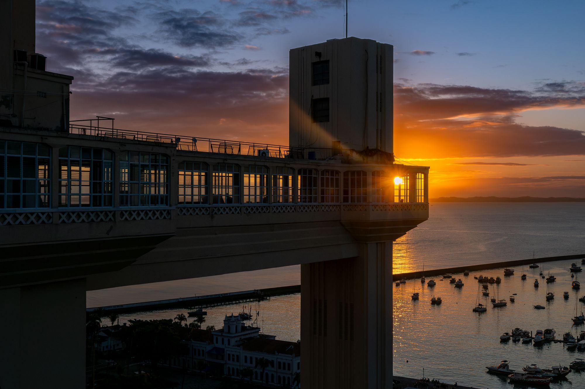The Lacerda Elevator above All Saints Bay in Salvador at sunset, with boats on the water.