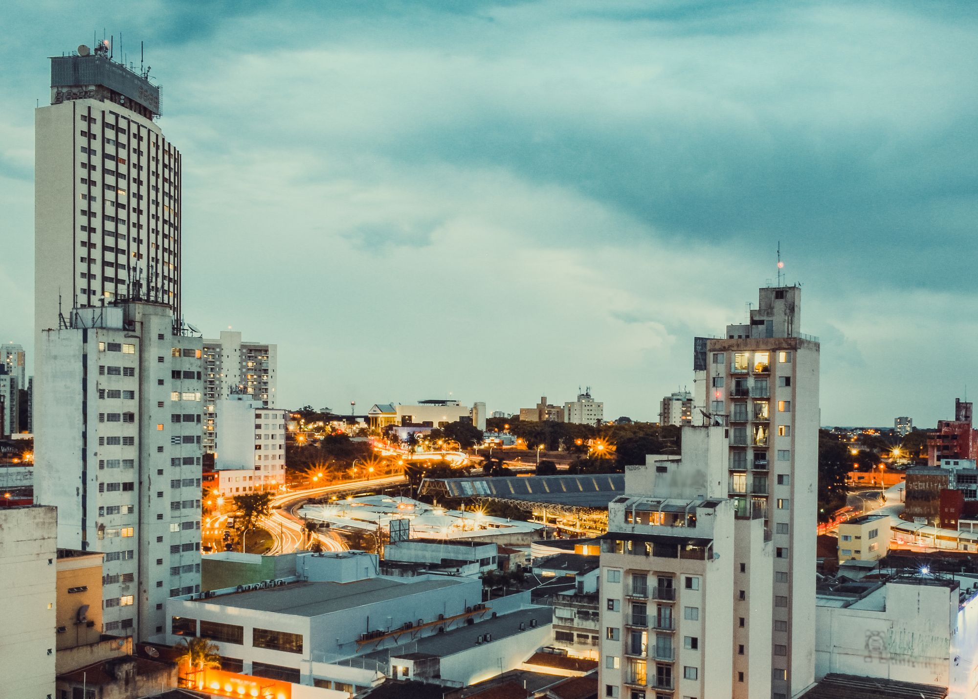 High-rise buildings in Campinas at dusk, with the city lights coming on.