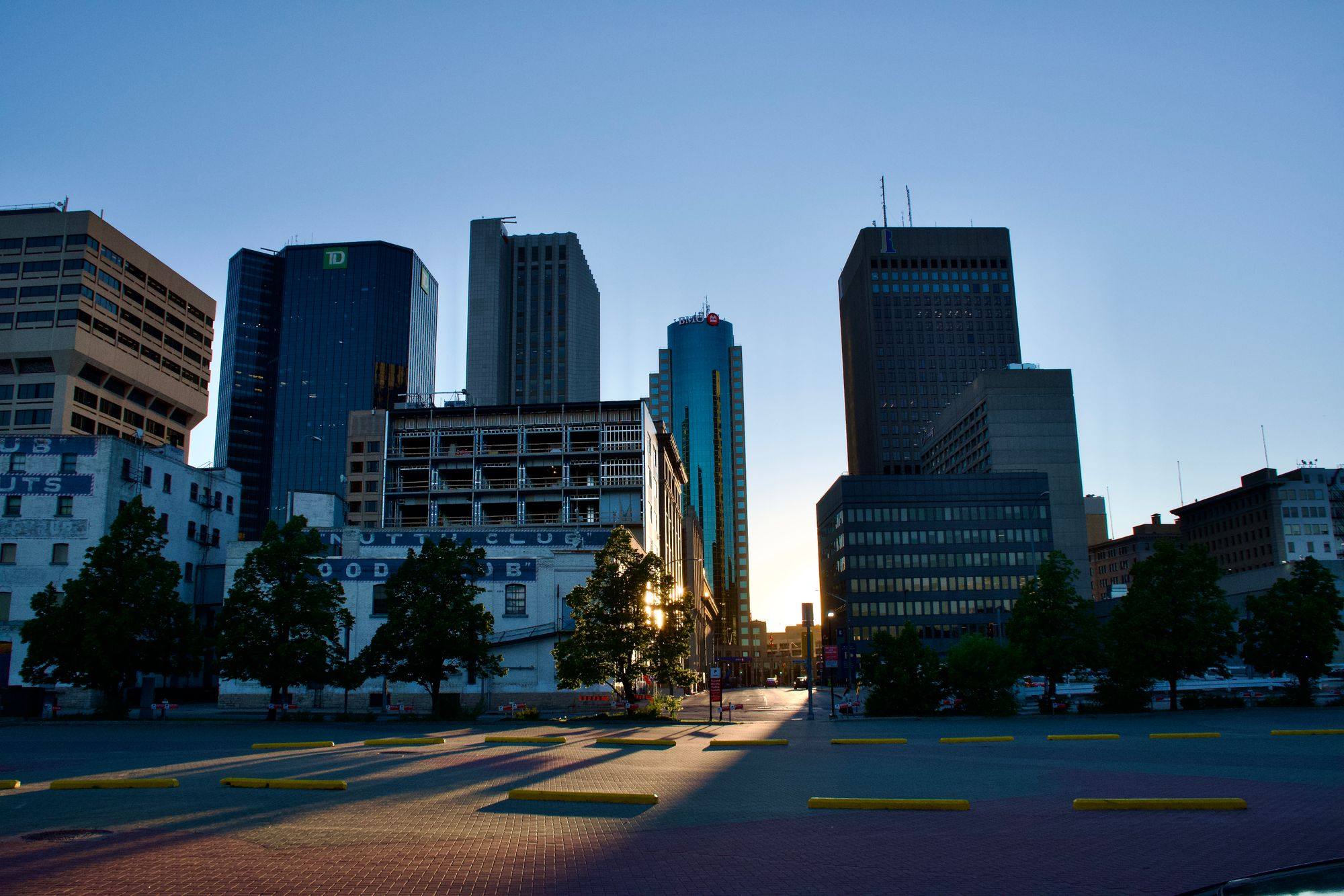 Downtown Winnipeg towers at sunset, seen along an empty street.