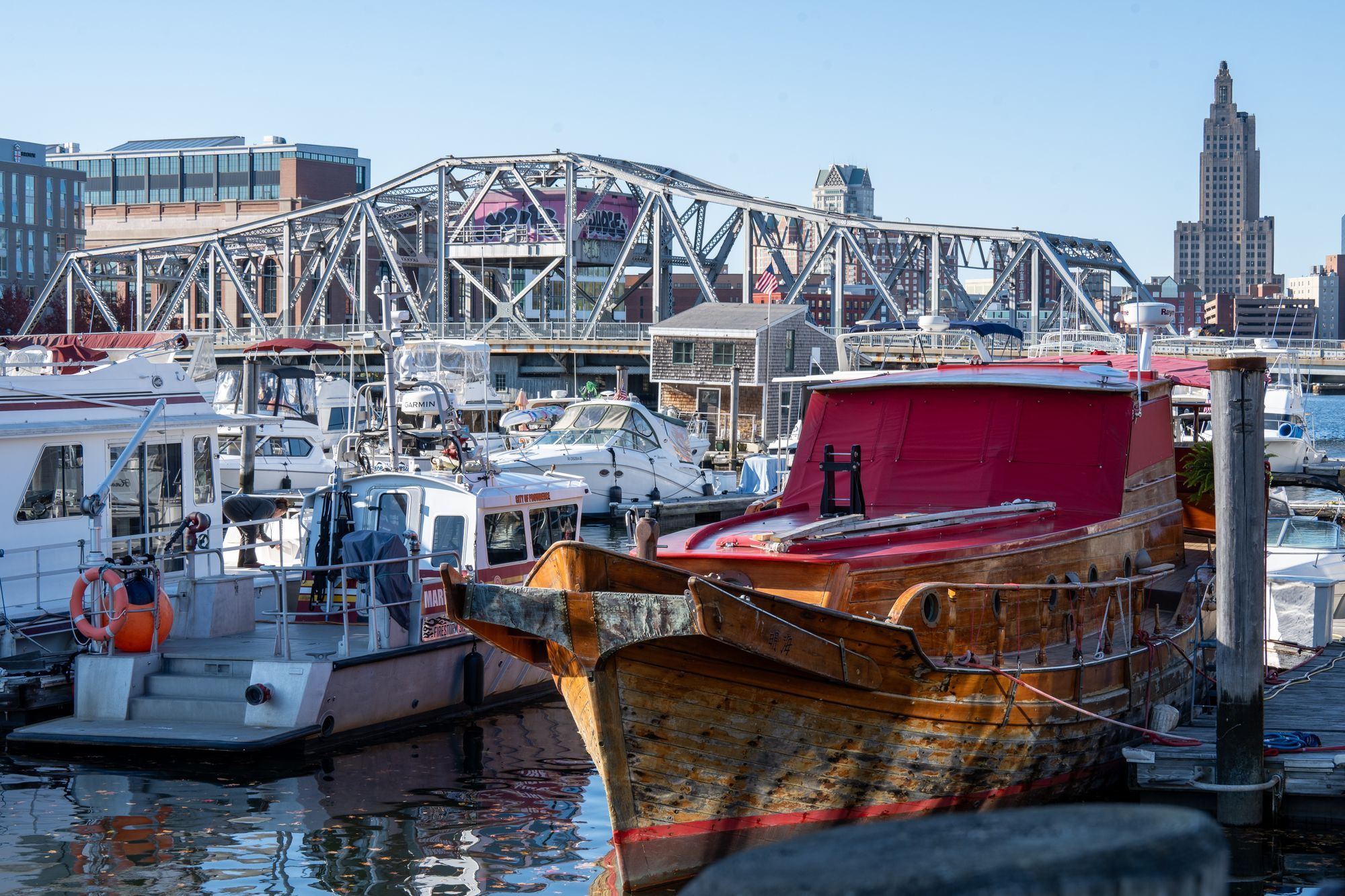 Boats at a marina on the Providence River with the downtown skyline behind.