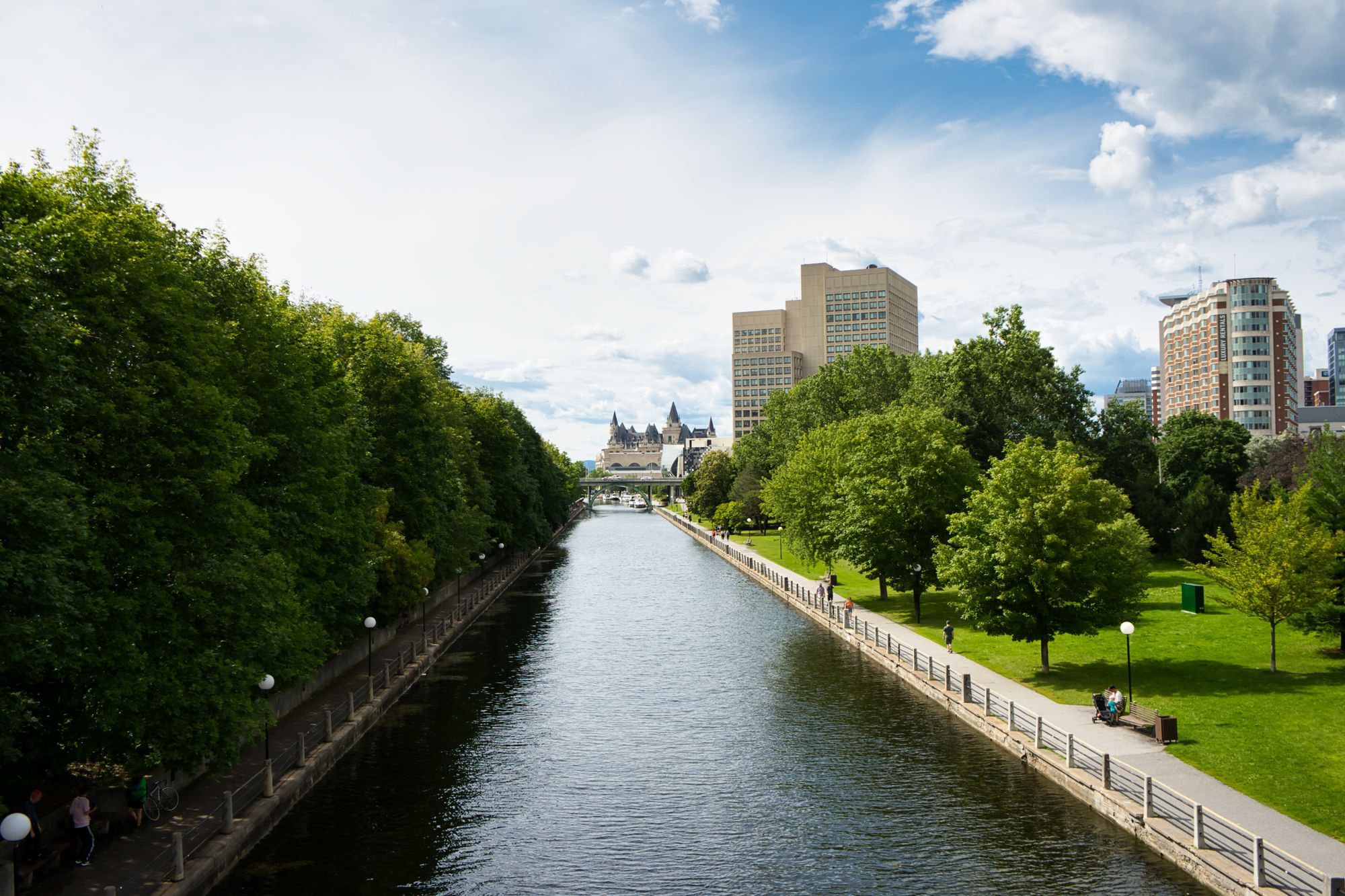 The Rideau Canal and its tree-lined footpath in Ottawa, with the Château Laurier in the distance.