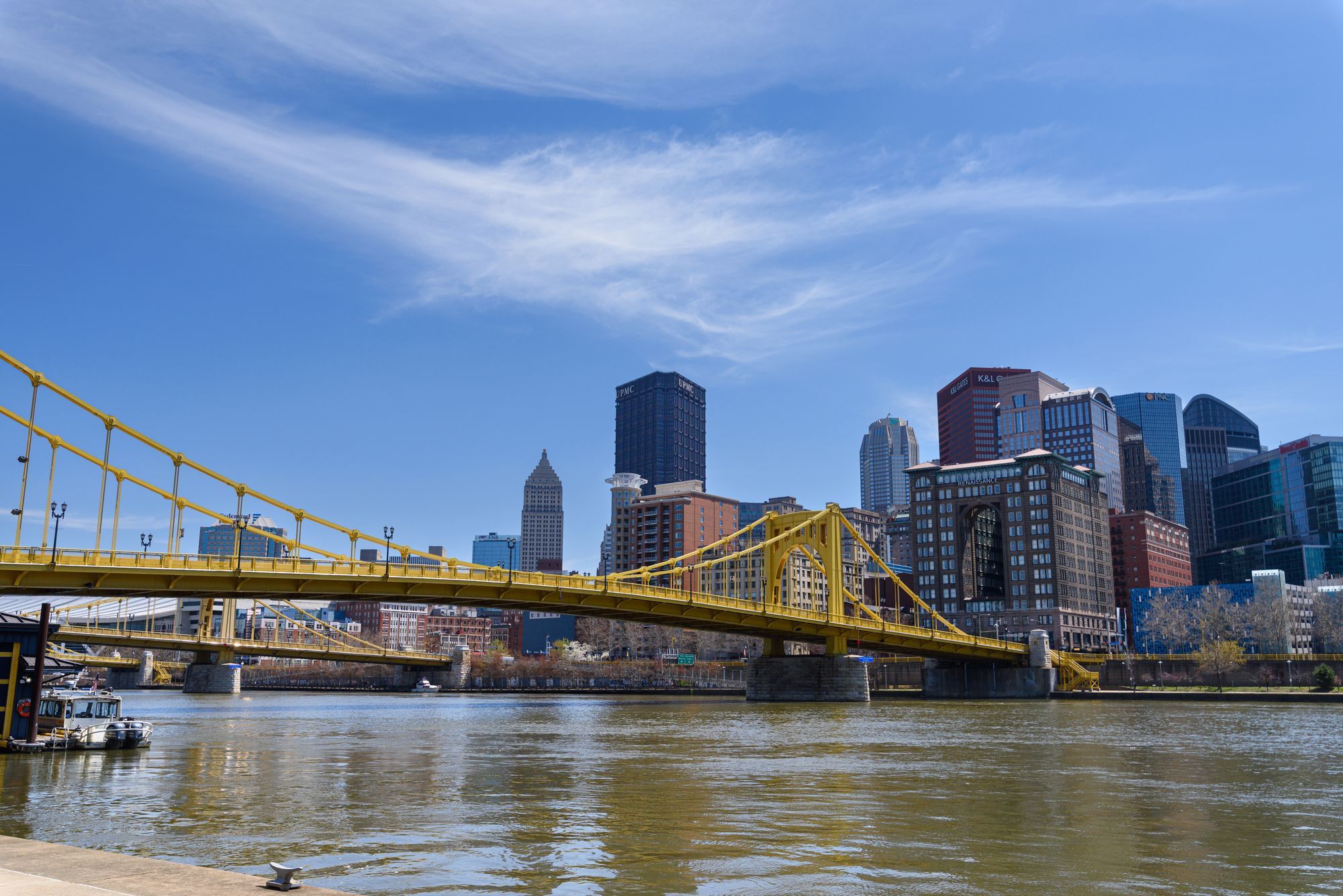 The yellow Roberto Clemente Bridge with the Pittsburgh skyline behind it on a clear day.