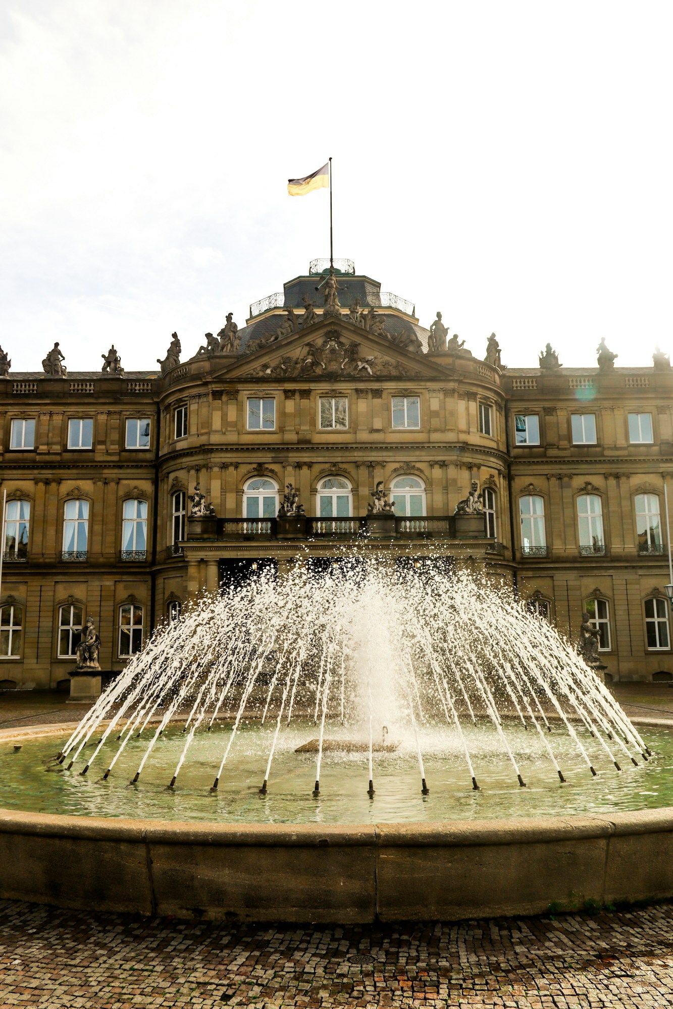 The New Palace in Stuttgart with its sculpted pediment and a fountain in front.