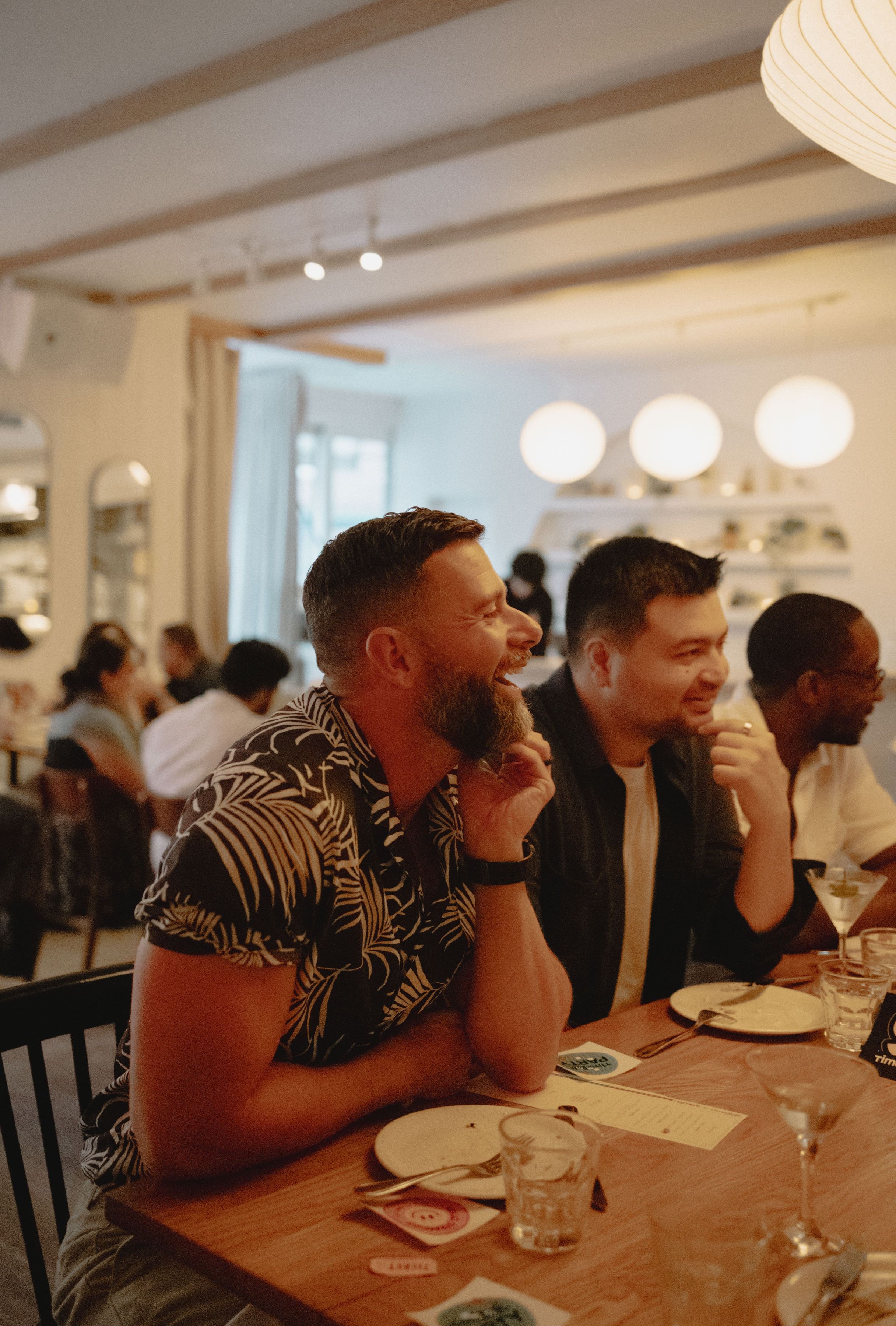 Three men laughing together at a Timeleft dinner table