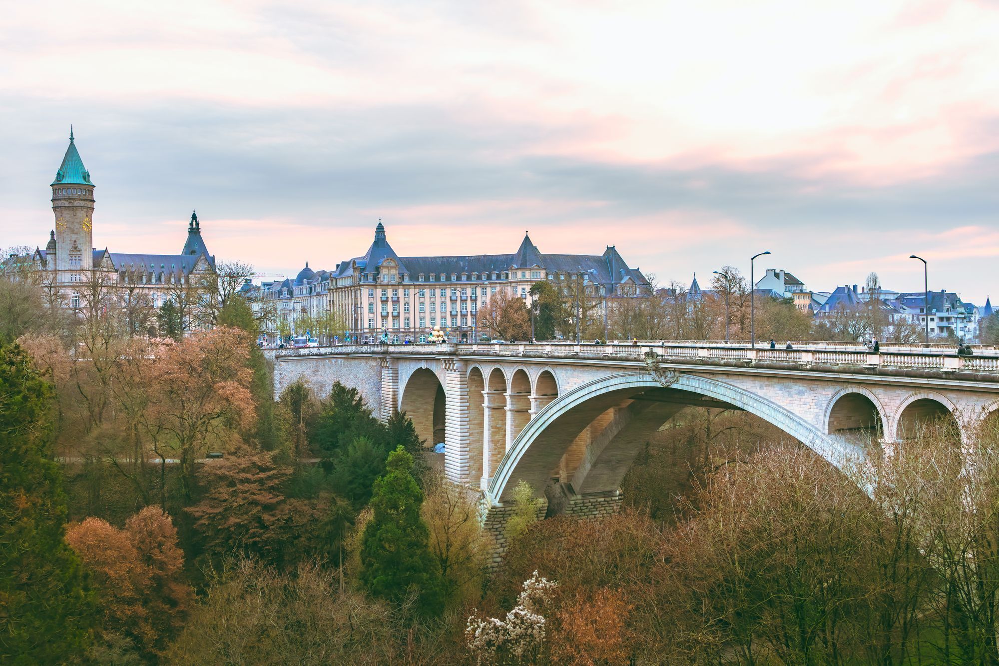 The Adolphe Bridge crossing the Pétrusse valley in Luxembourg City, with the old town skyline behind and autumn trees below.