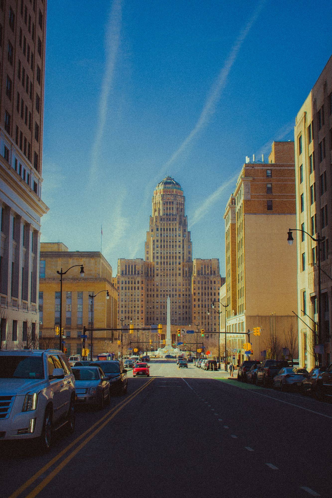 Buffalo City Hall at the end of a downtown street in warm evening light.