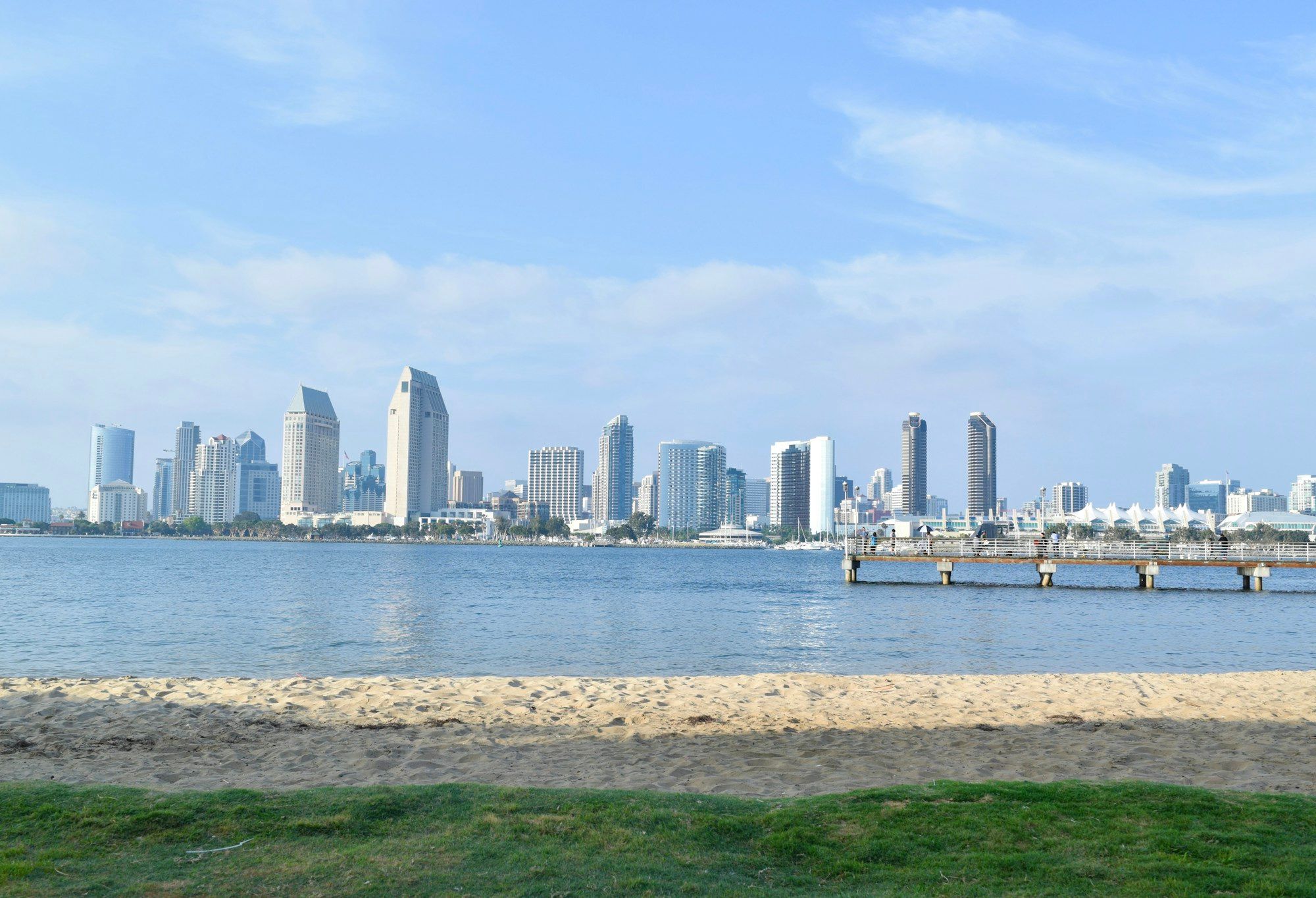 The downtown San Diego skyline seen across the bay from Coronado, with a small beach in front.