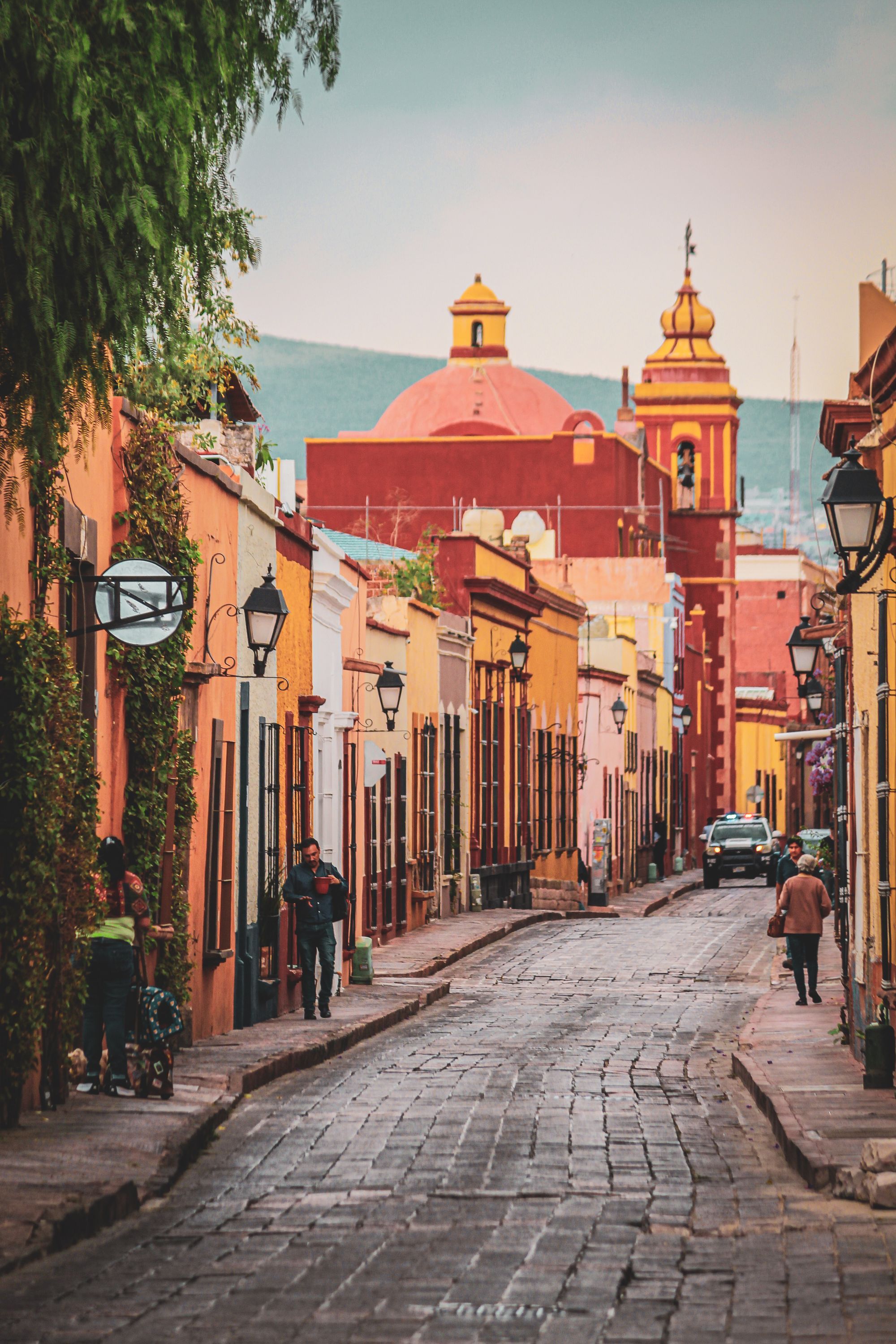 A colorful colonial street leading to a domed church in the historic center of Querétaro.
