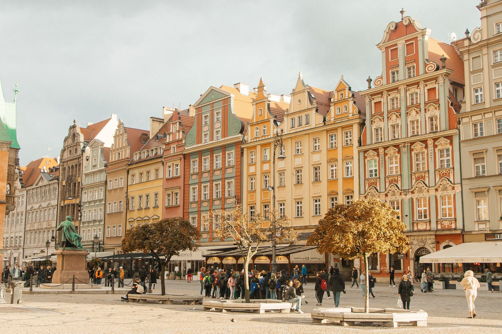 The coloured townhouses on Wrocław's Market Square with people on the square in autumn.