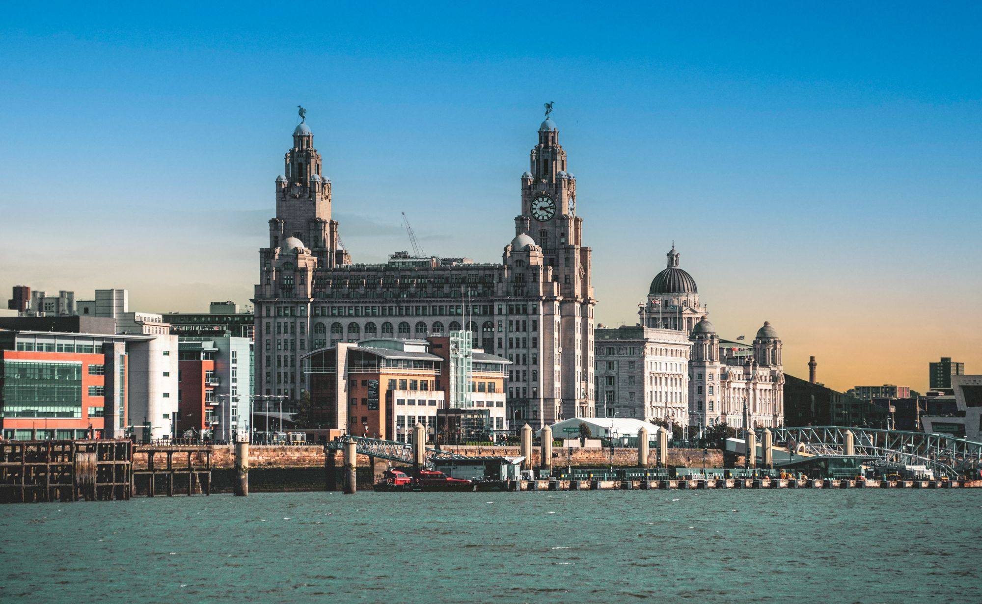 The Royal Liver Building and the Three Graces seen across the River Mersey in Liverpool at dusk.