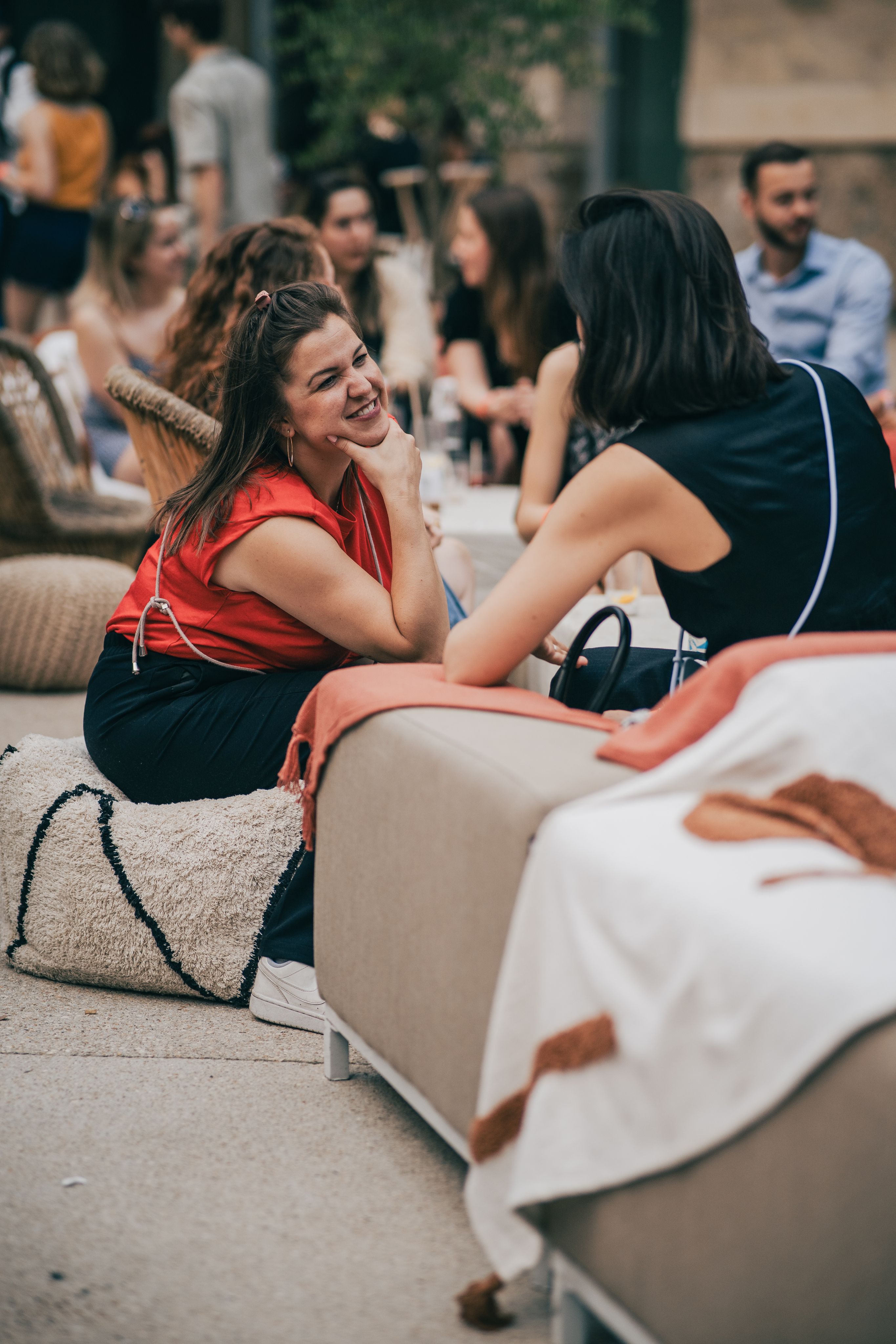 Two women talking and smiling in a busy outdoor lounge