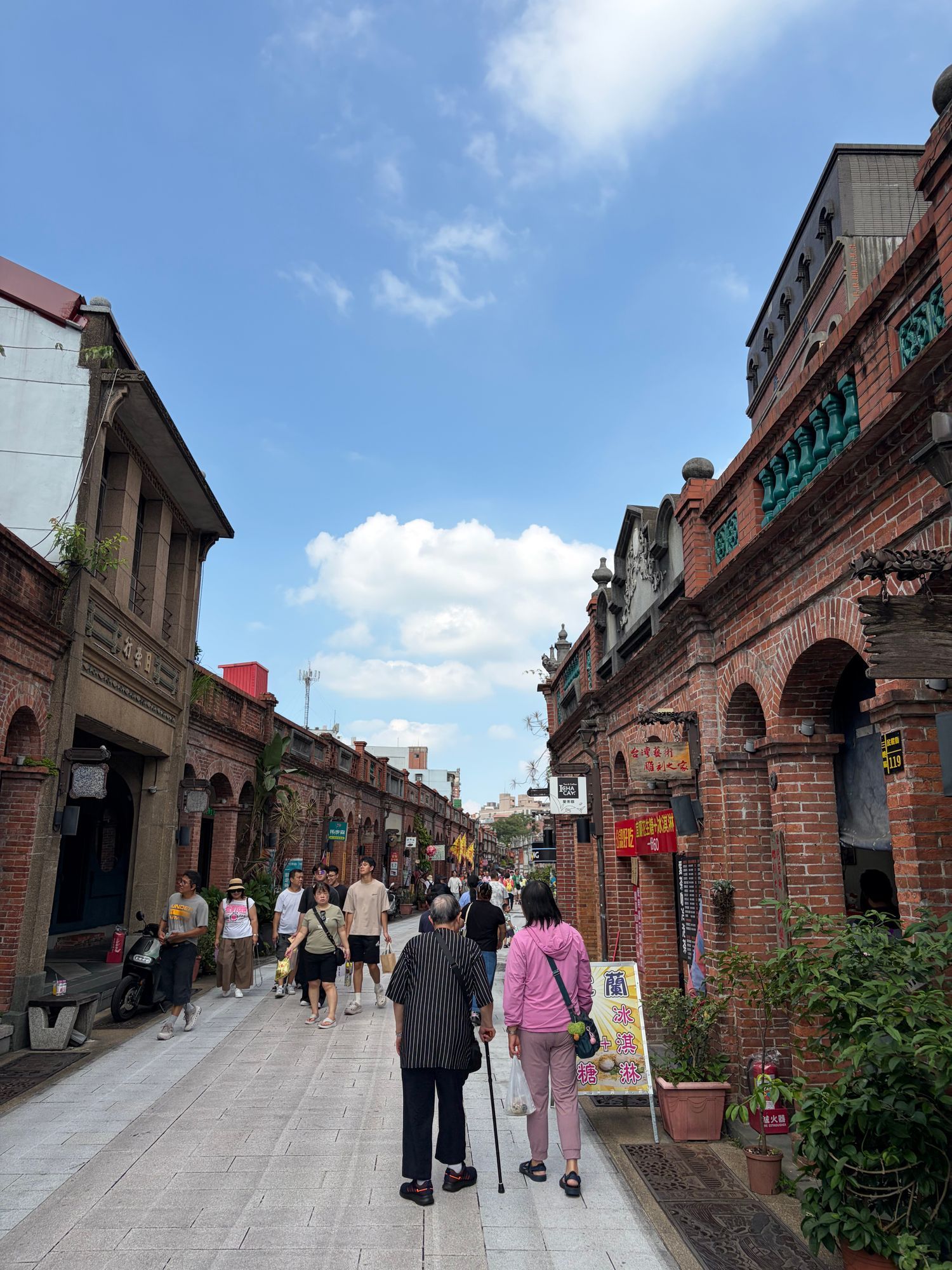 Brick arcaded shopfronts on Daxi Old Street in Taoyuan City, with visitors walking along the street.