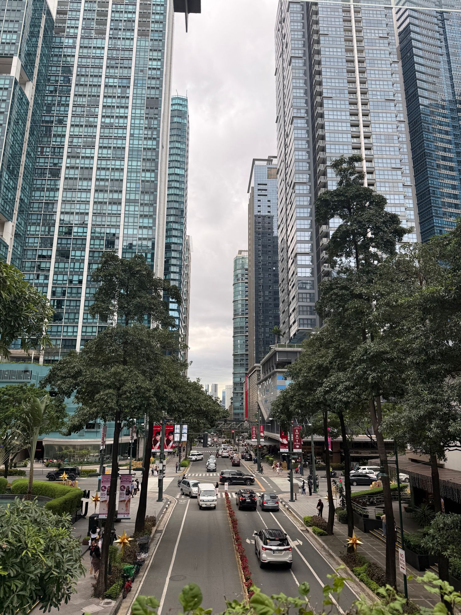 Makati Avenue lined with trees and high-rise towers, with traffic below.
