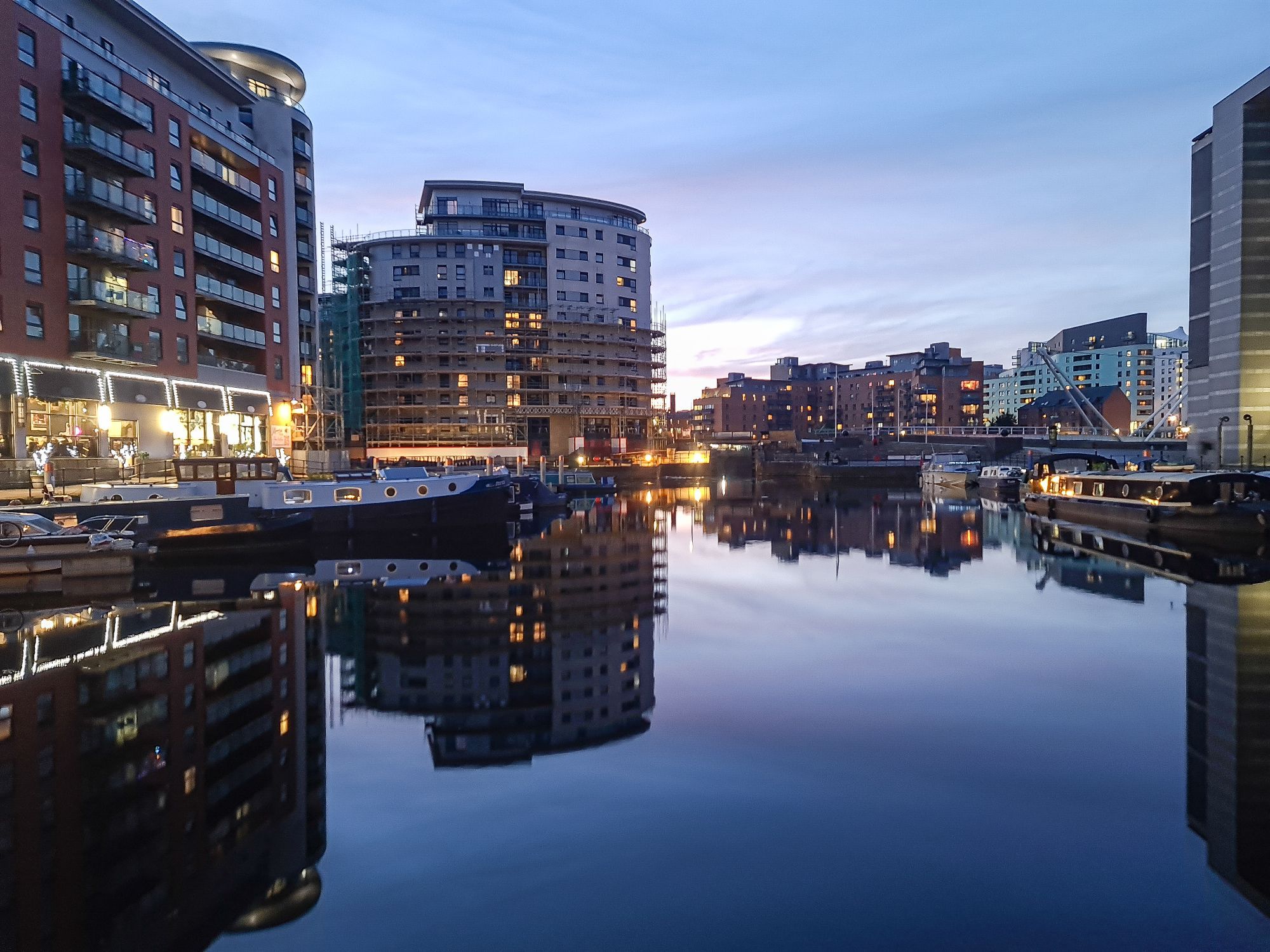 Apartment blocks reflected in the water at Leeds Dock at dusk.