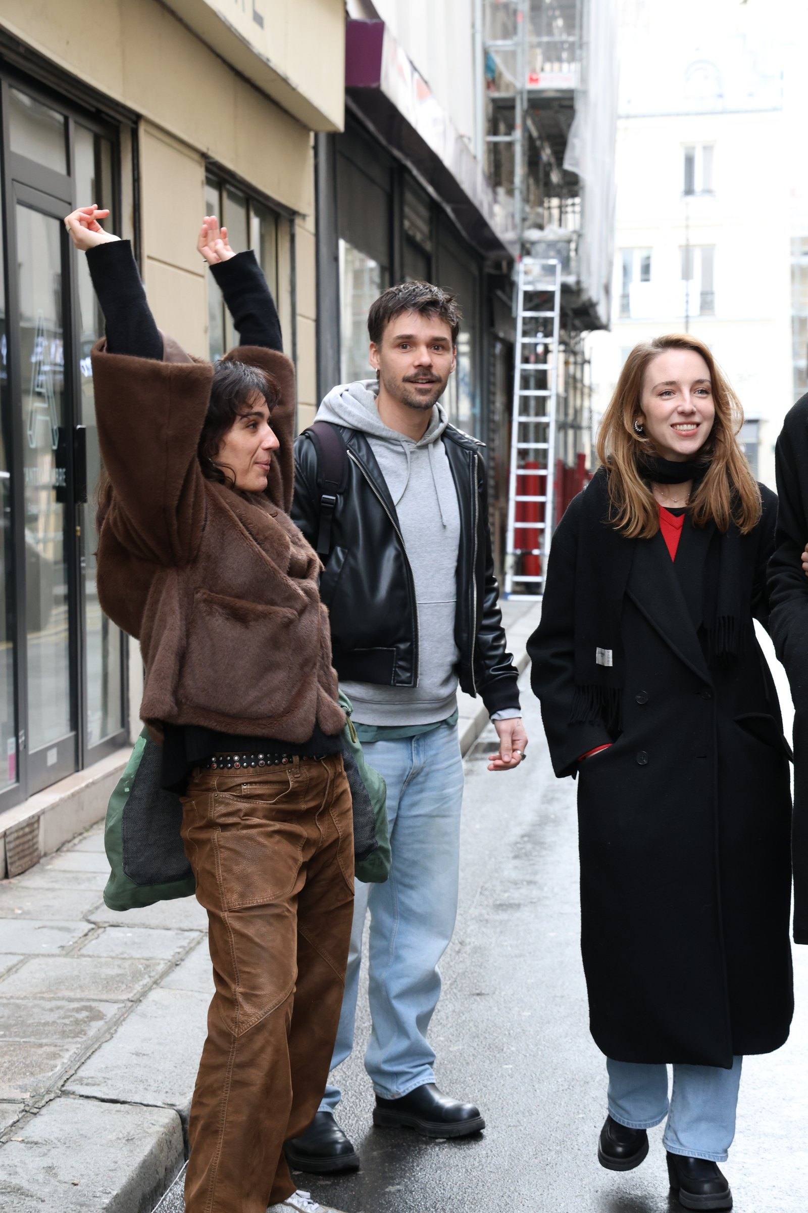 One walker throws an arm up mid-step while two friends walk alongside